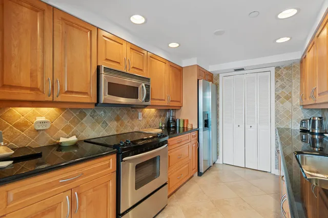 a kitchen with stainless steel appliances granite countertop a stove a sink and a microwave