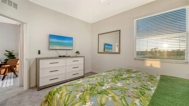 a bedroom with a bed and a flat tv screen on dresser