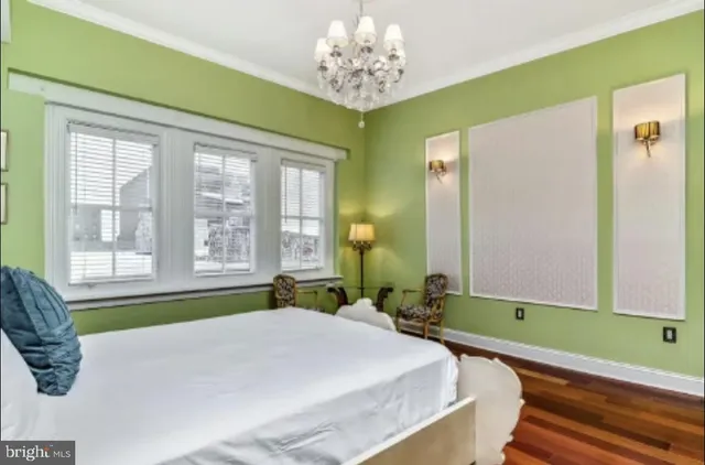 a bedroom with a bed a chair and painting on the wall