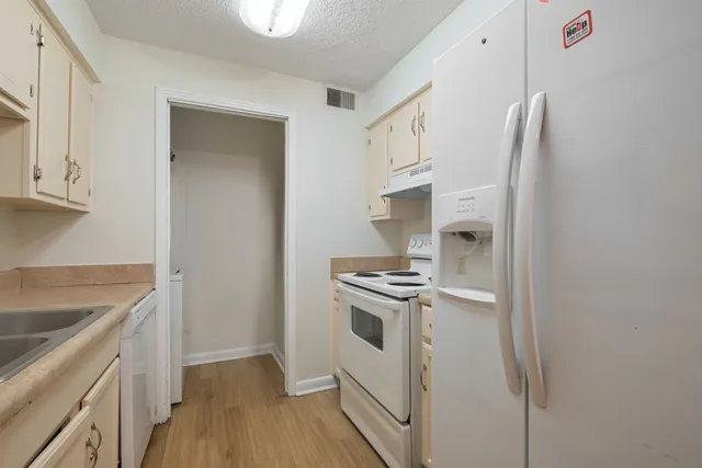 a kitchen with stainless steel appliances granite countertop a refrigerator a stove and a sink with wooden floor