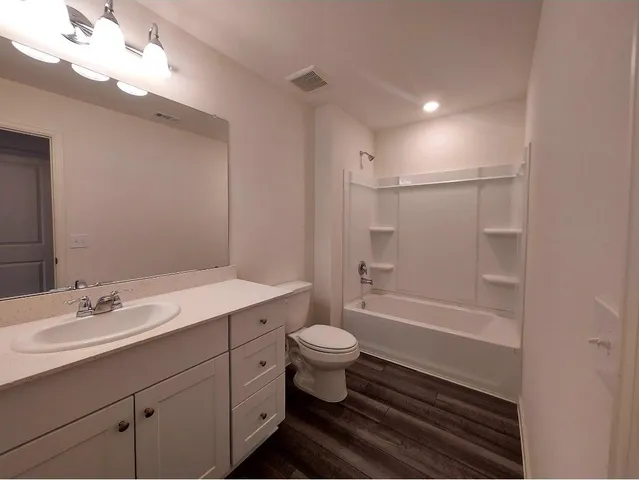 a bathroom with a sink a toilet a mirror and shower