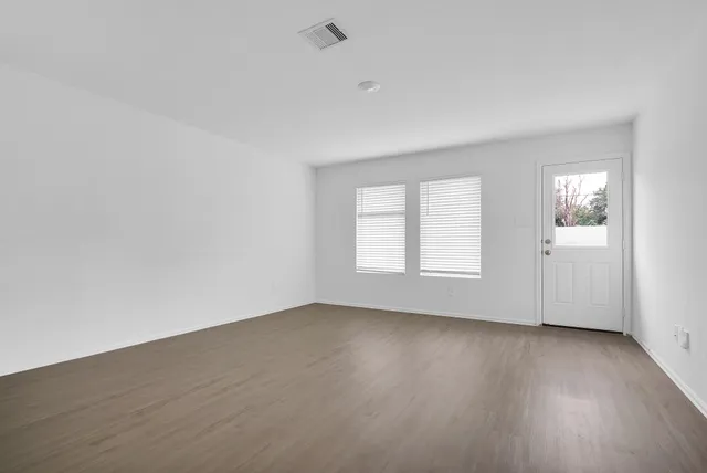 an empty room with wooden floor and windows