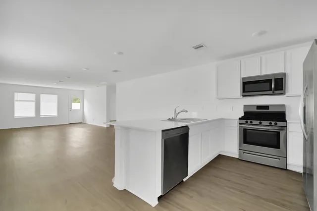 a kitchen with stainless steel appliances a stove a sink a microwave and wooden cabinets