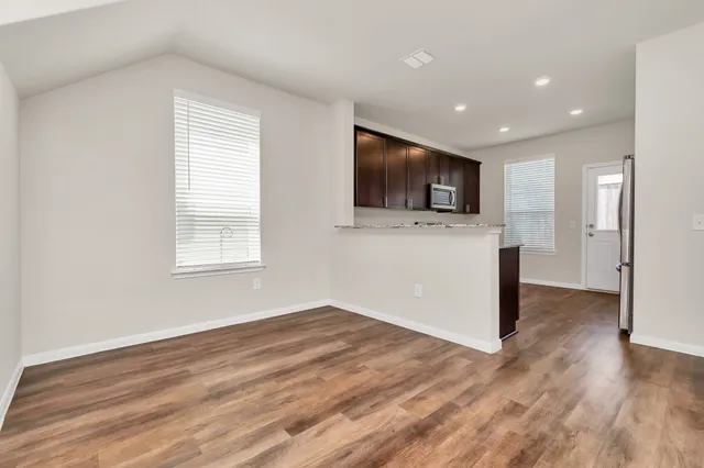 a view of empty room with wooden floor and window