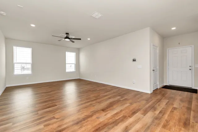 a view of an empty room with a window and wooden floor