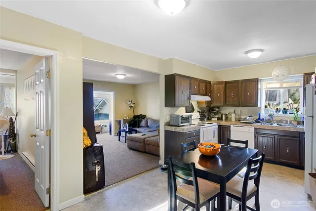 a kitchen view with stainless steel appliances kitchen island granite countertop a table and chairs in it