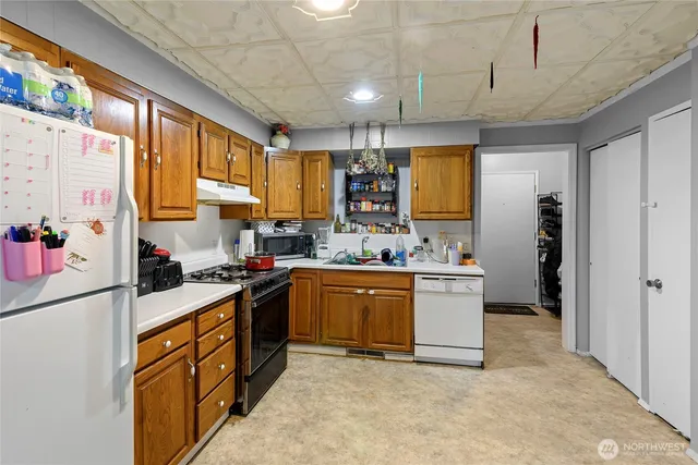 a kitchen with stainless steel appliances granite countertop a refrigerator a sink dishwasher a stove and white countertops with wooden floor