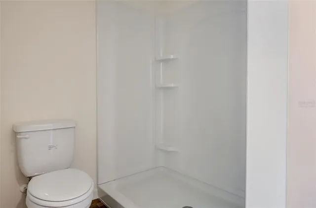 a white toilet sitting next to a shower