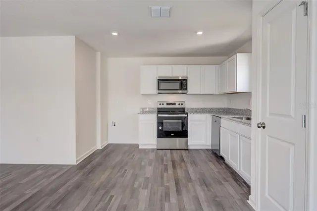 a kitchen with granite countertop a refrigerator stove top oven and sink