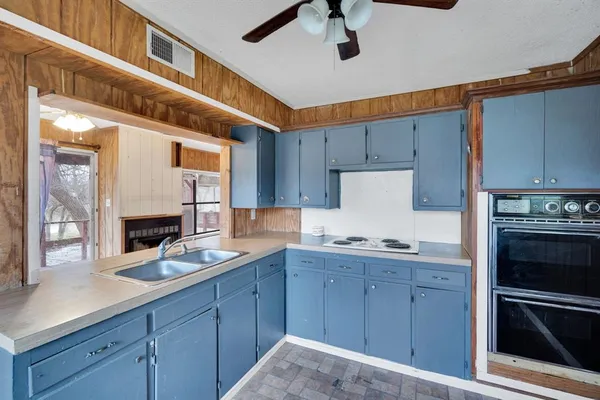 a kitchen with stainless steel appliances granite countertop a stove a refrigerator a sink a dining table and chairs with wooden floor