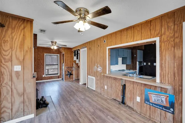 a view of an empty room with chandelier fan and wooden floor