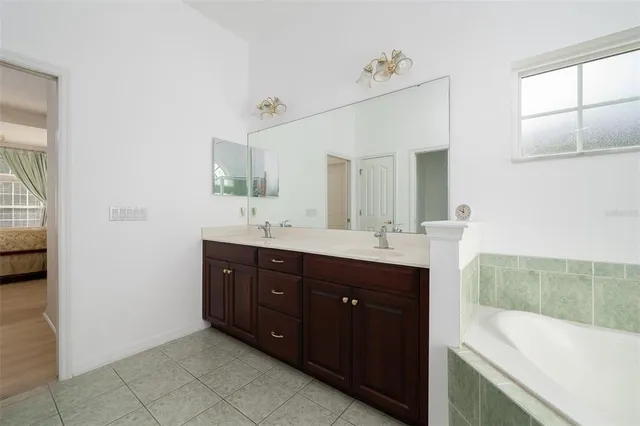 a spacious bathroom with a tub sink and mirror