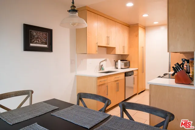 a kitchen with stainless steel appliances granite countertop a sink dishwasher a stove a dining table and chairs with wooden floor