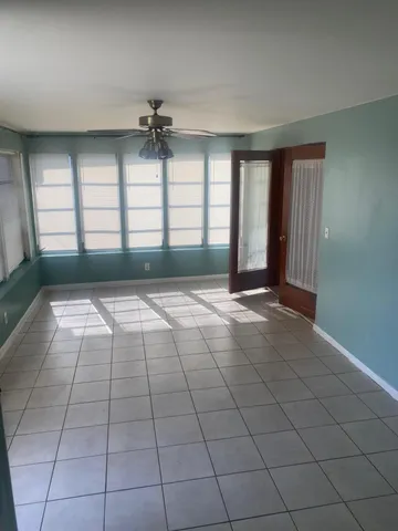 an empty room with windows and fan
