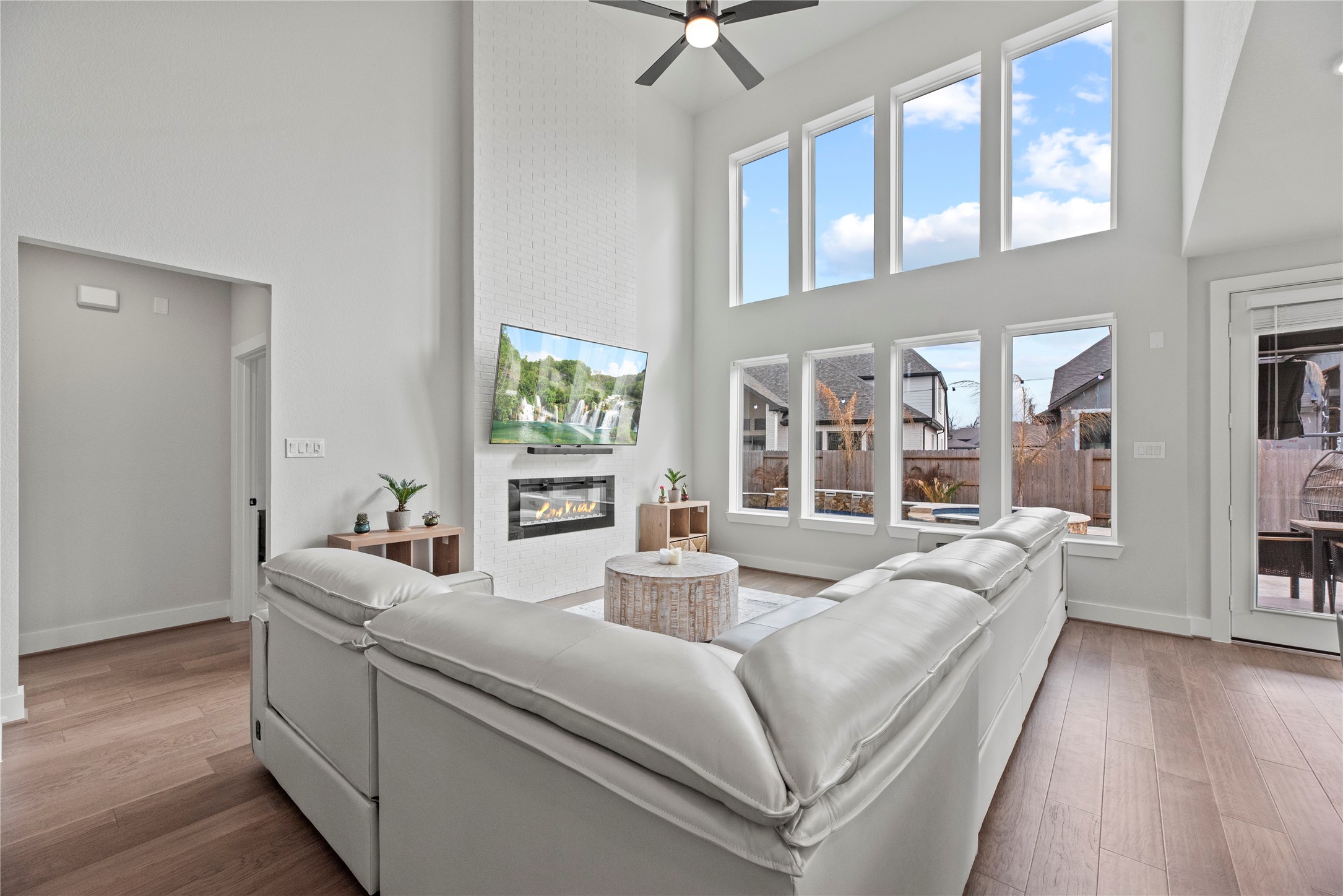 30155 GOLD FINCH Place Fulshear, TX 77441 - Photo 4 of 26 Sun-drenched living space with dramatic two-story ceiling, sleek engineered wood planks, cozy fireplace, tons of charm!
