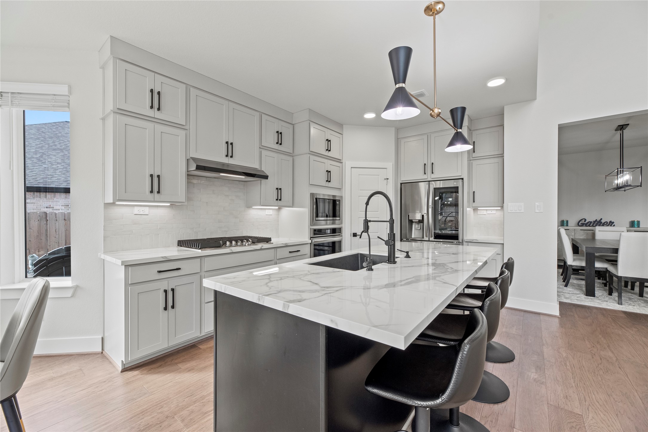 30155 GOLD FINCH Place Fulshear, TX 77441 - Photo 7 of 26 The kitchen features a coordinating backsplash and rich white cabinetry with under-cabinet lighting, adding a refined touch and elevating the overall feel of the space.