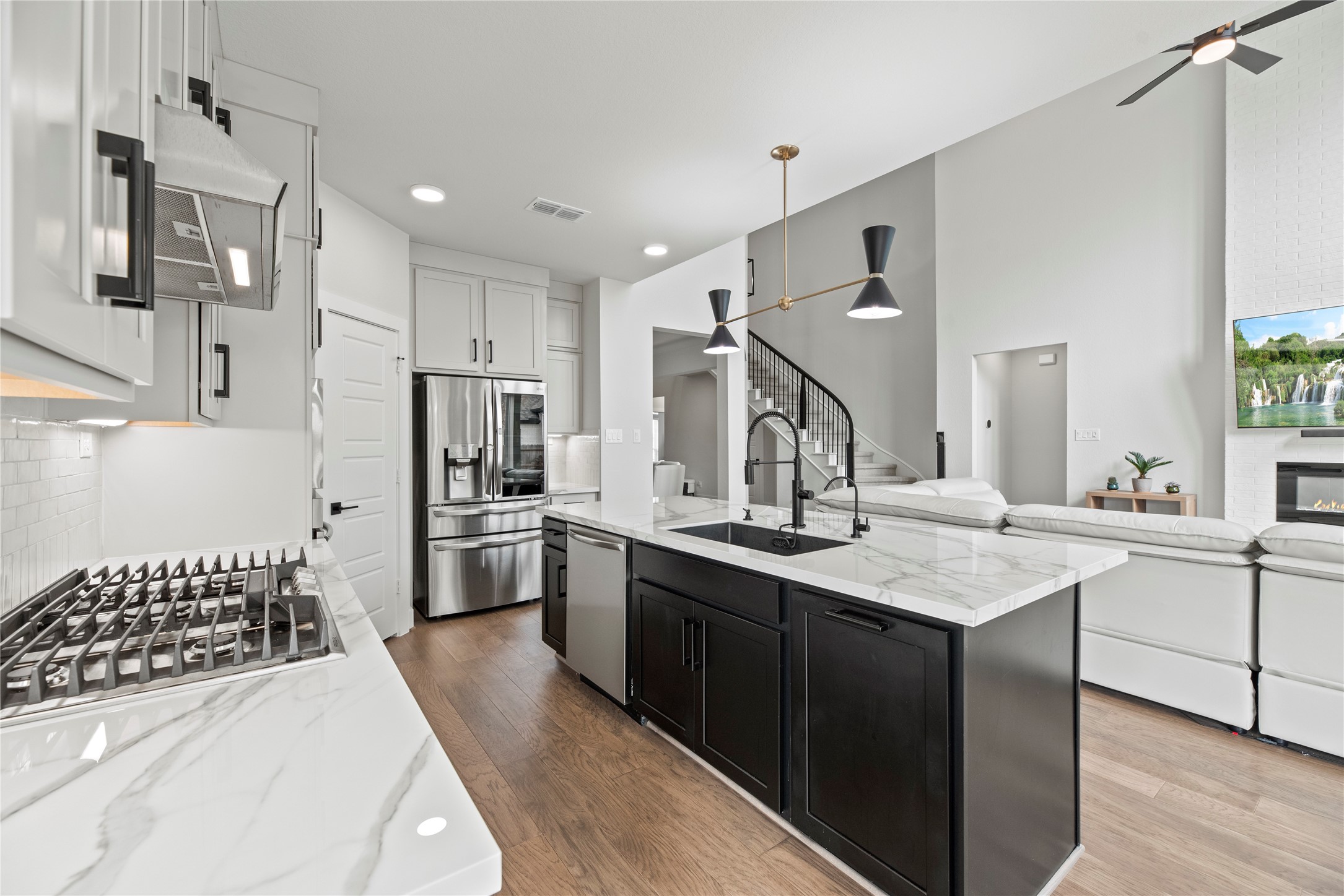 30155 GOLD FINCH Place Fulshear, TX 77441 - Photo 8 of 26 Stainless steel appliances anchor the kitchen, featuring a large gas range with a matching vent hood, a built-in dishwasher, and an undermount sink, creating a well-planned space that supports both daily cooking and entertaining.