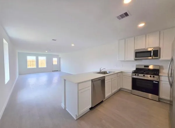 a kitchen with stainless steel appliances granite countertop white cabinets and window