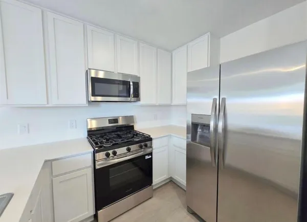 a kitchen with stainless steel appliances granite countertop a refrigerator stove and microwave