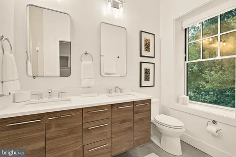 a bathroom with a toilet a sink a large mirror and next to a window