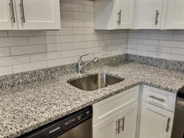 a kitchen with granite countertop white cabinets and a sink