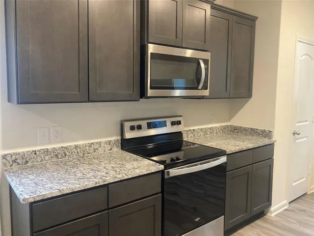 a kitchen with granite countertop cabinets stainless steel appliances and a counter space