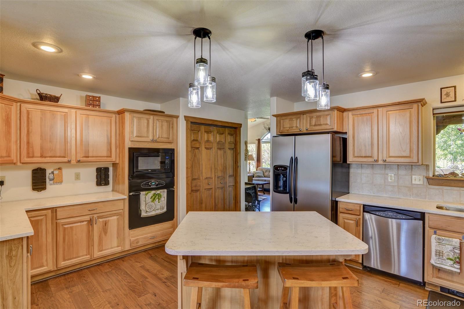 3135 Singletree Road Hartsel, CO 80449 - Photo 10 of 40 a kitchen with stainless steel appliances kitchen island granite countertop a refrigerator a stove and white cabinets with wooden floors