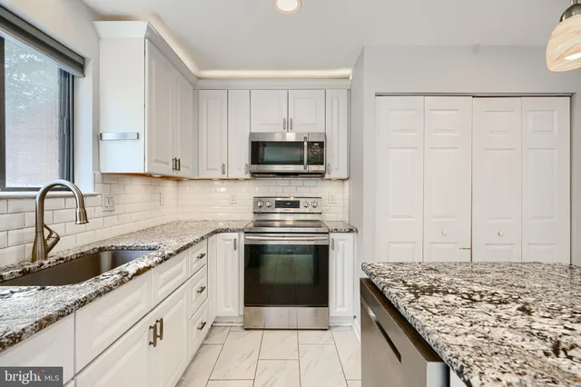 a kitchen with granite countertop a sink stove and cabinets