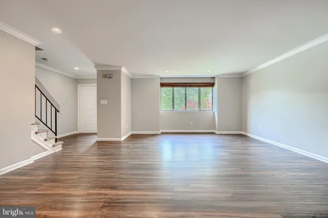 a view of an empty room with window and wooden floor