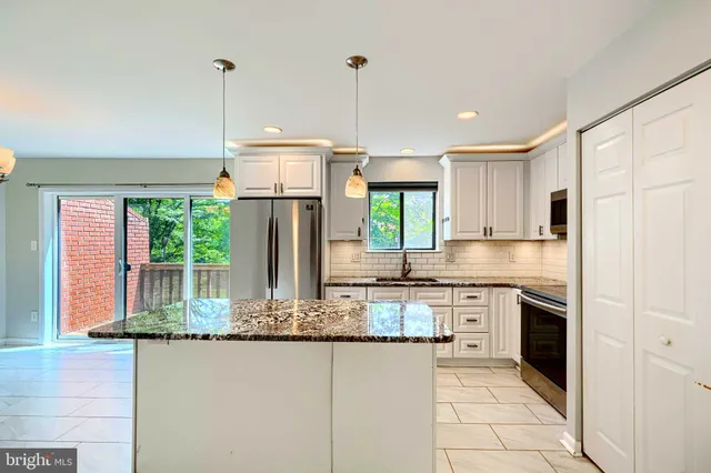 a kitchen with kitchen island granite countertop a stove a sink and a refrigerator
