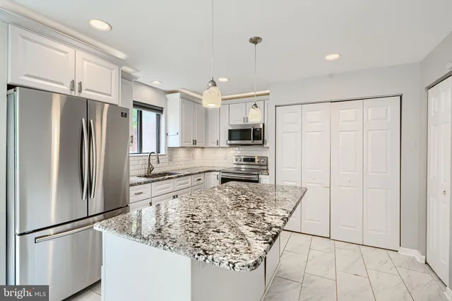 a kitchen with stainless steel appliances granite countertop a refrigerator and a stove top oven