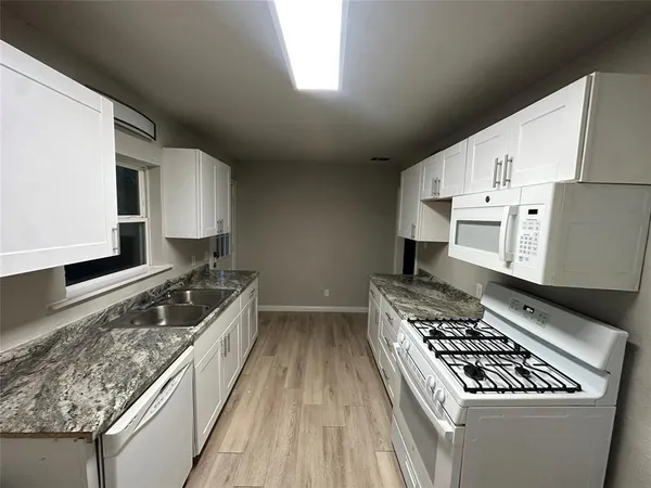 a kitchen with granite countertop a sink stove and cabinets