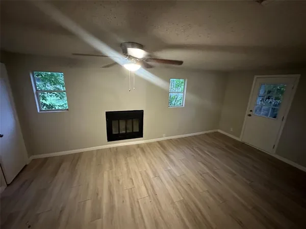 a view of an empty room with a window and wooden floor
