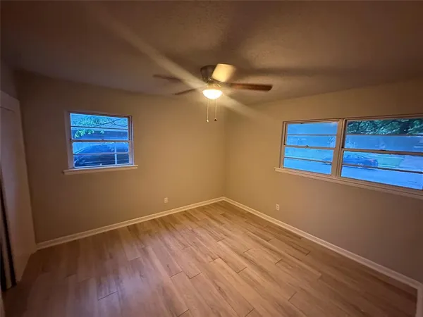 a view of a room with wooden floor and a ceiling fan
