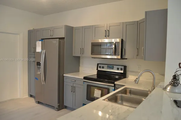 a kitchen with stainless steel appliances a refrigerator a sink a stove a microwave and cabinets