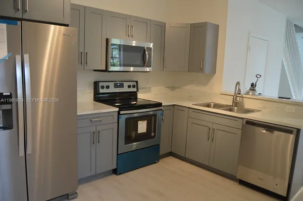 a kitchen with refrigerator a microwave a sink and cabinets