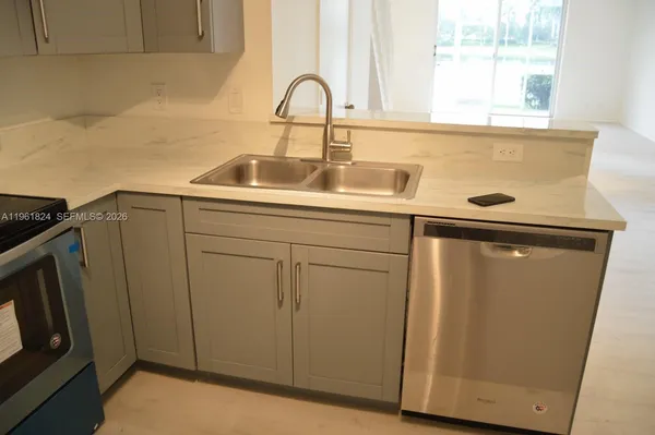 a close view of a sink and dishwasher with wooden cabinets
