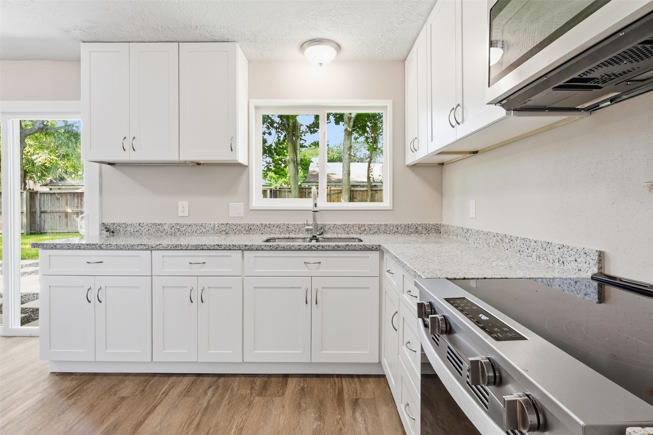 4767 Beechaven Street Houston, TX 77053 - Photo 11 of 26 a kitchen with granite countertop a stove a sink and dishwasher with wooden floor