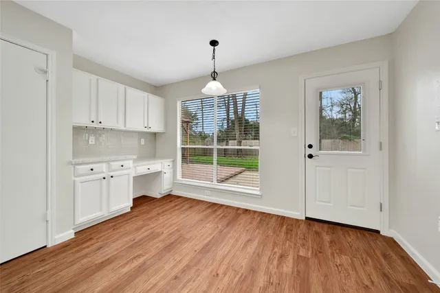 a open kitchen with granite countertop a stove top oven a sink dishwasher and white cabinets with wooden floor