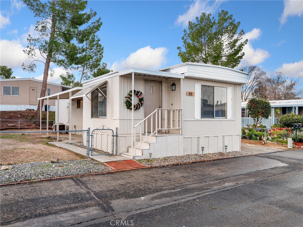 11414 Serra Road, Unit 46 Apple Valley, CA 92308 - Photo 1 of 22 a view of a white house with large windows and a small yard