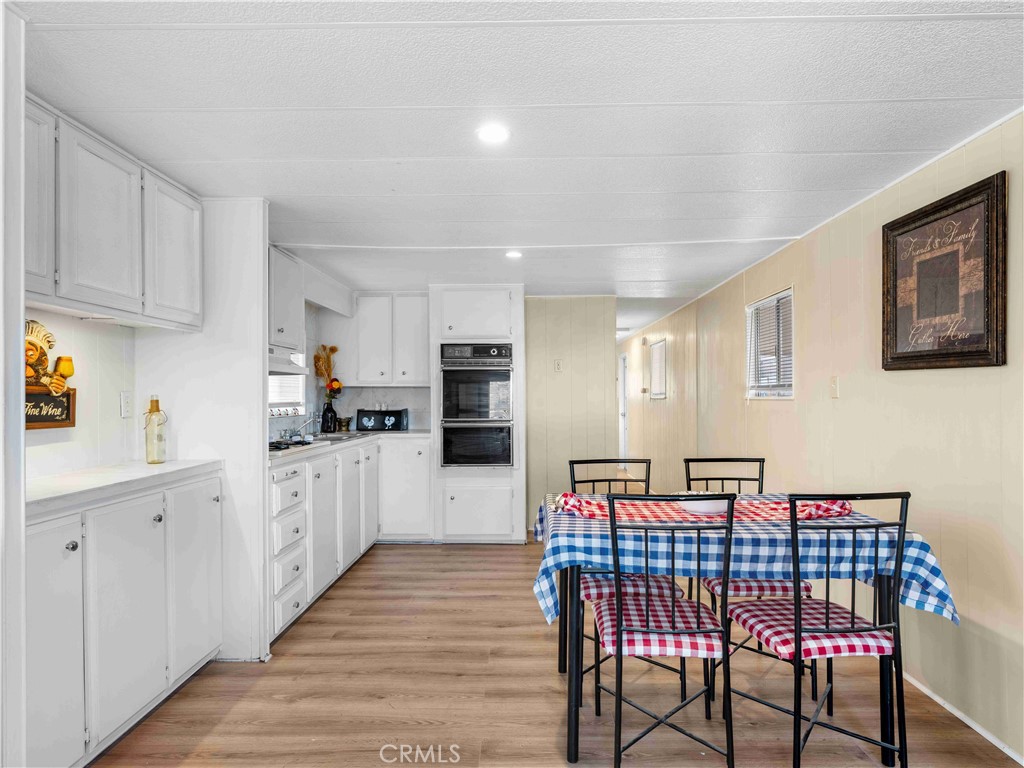 11414 Serra Road, Unit 46 Apple Valley, CA 92308 - Photo 7 of 22 a kitchen with stainless steel appliances kitchen island granite countertop a refrigerator a sink dishwasher a dining table and chairs with wooden floor