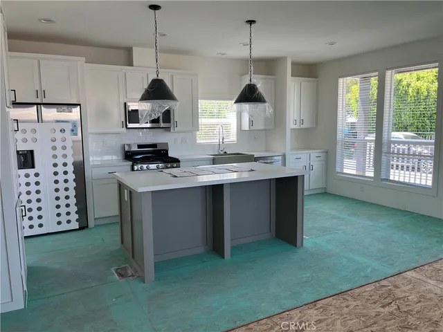 a kitchen with stainless steel appliances granite countertop a stove a sink a refrigerator and a window