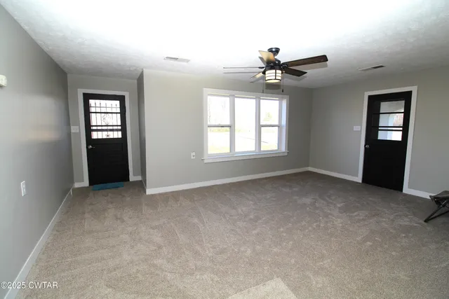 an empty room with windows and ceiling fan