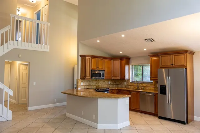 a kitchen with stainless steel appliances granite countertop a refrigerator a stove and a sink