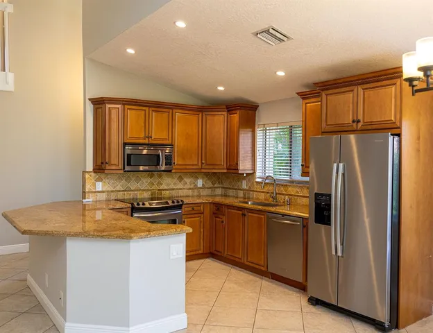 a kitchen with stainless steel appliances granite countertop a refrigerator a sink dishwasher a stove and a refrigerator with wooden floor