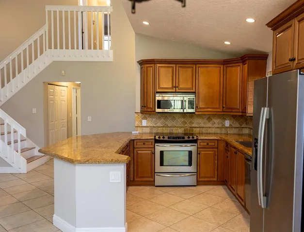 a kitchen with stainless steel appliances granite countertop a stove a sink and a refrigerator