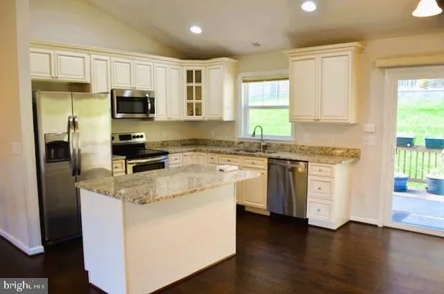a kitchen with stainless steel appliances granite countertop a sink a stove a refrigerator cabinets and a window