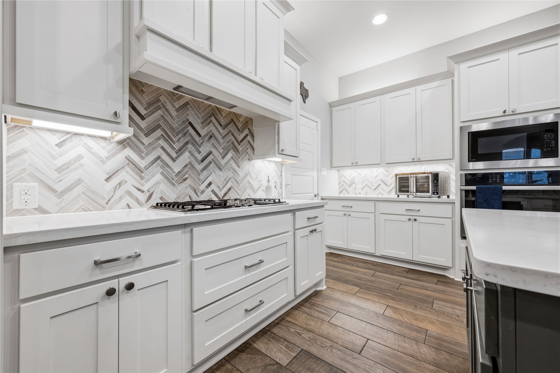 140 Catani Loop Georgetown, TX 78628 - Photo 18 of 36 White cabinetry, sleek countertops, and a herringbone tile backsplash define this elegant, functional kitchen.