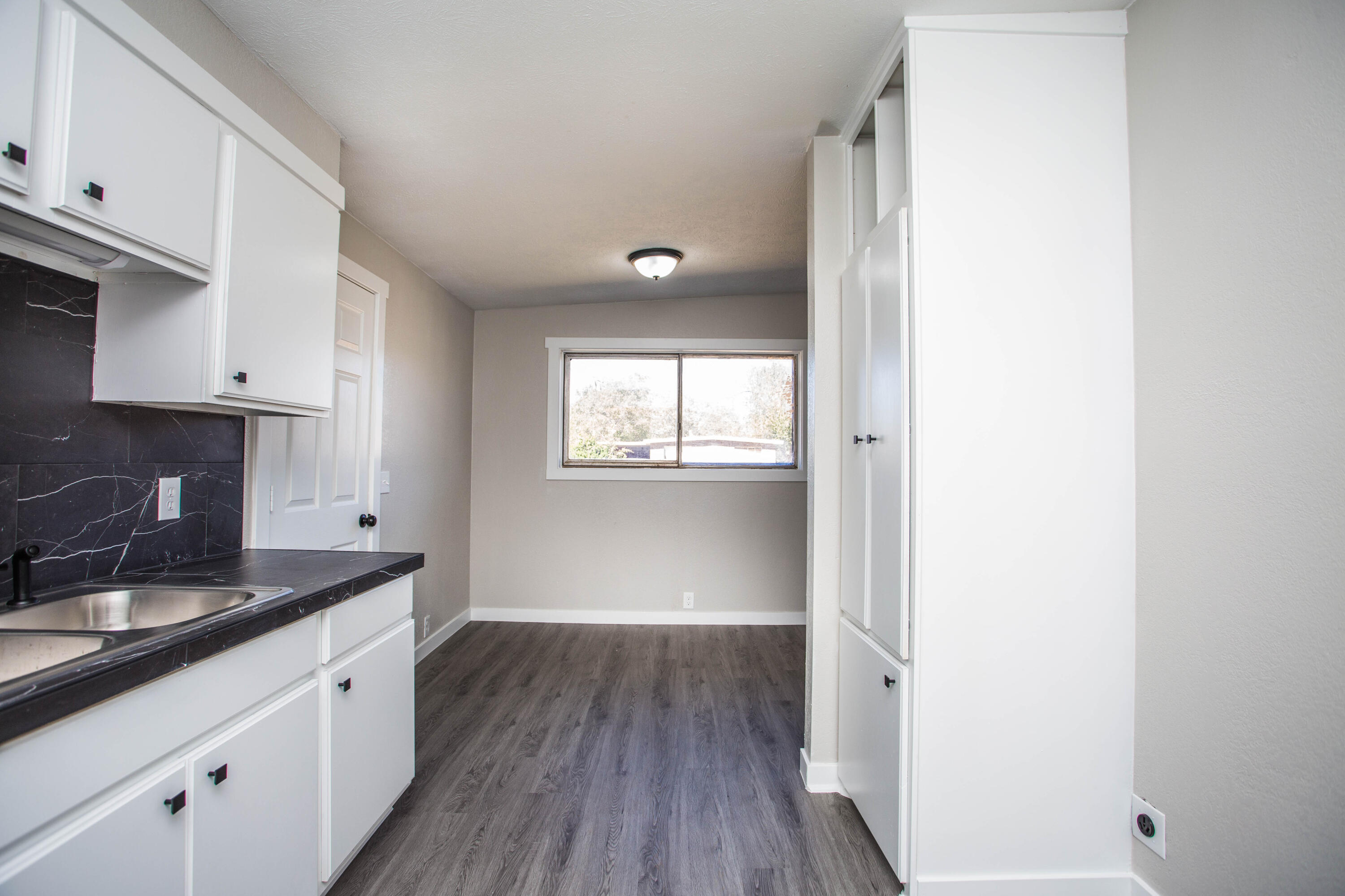 2725 63rd Street Lubbock, TX 79413 - Photo 7 of 42 a kitchen with granite countertop white cabinets and a wooden floor
