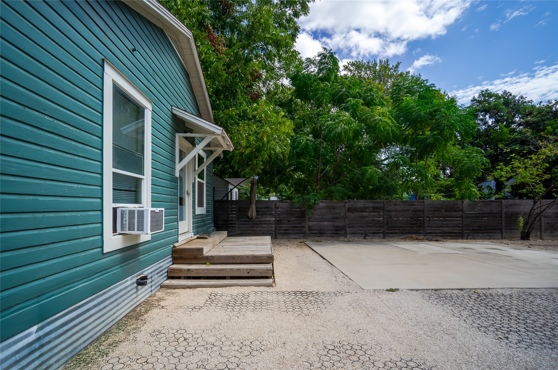719 Springdale Road Austin, TX 78702 - Photo 15 of 17 A private backyard oasis with a charming teal-sided structure, offering a spacious concrete pad perfect for outdoor entertaining.